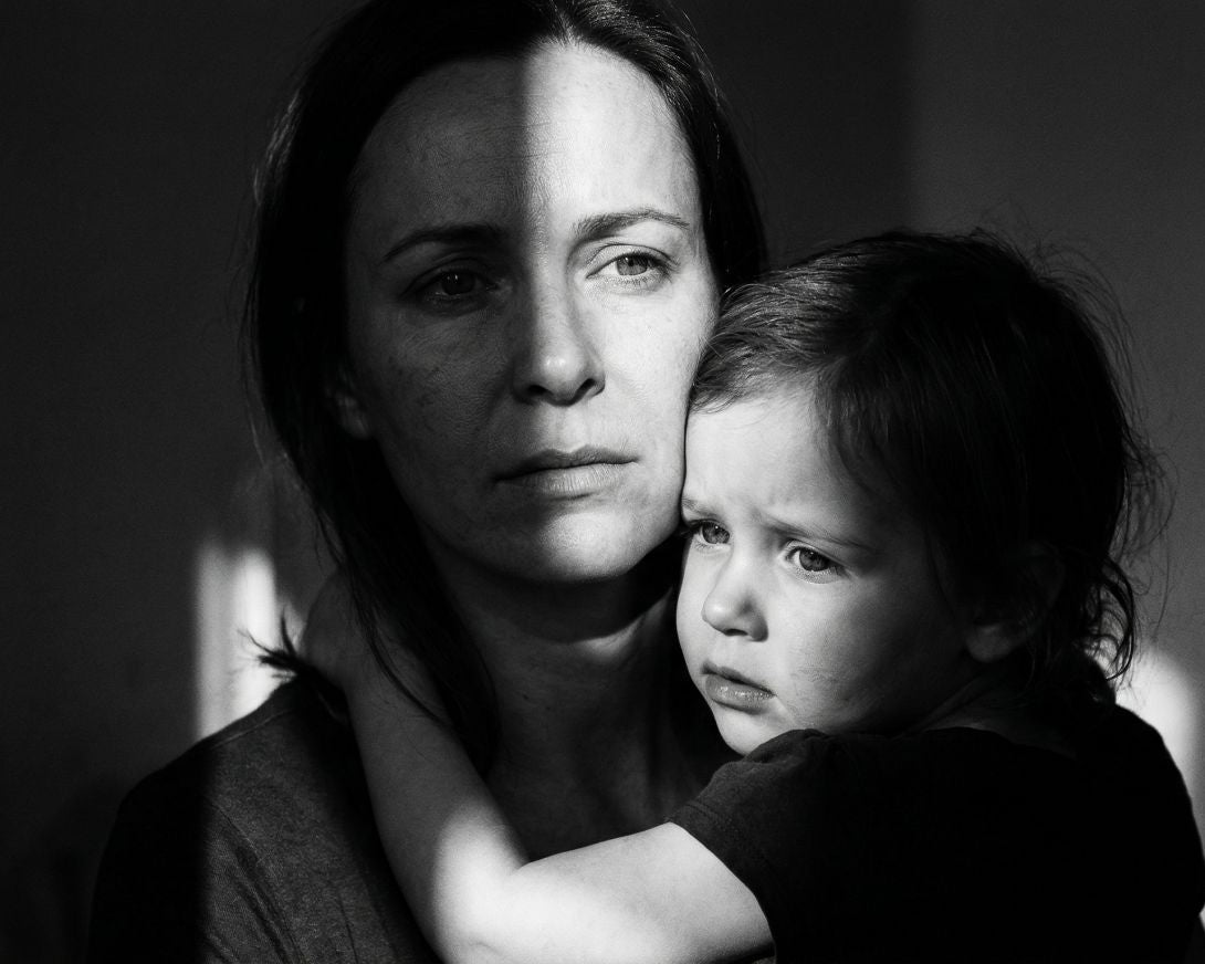 Black and white photo of a woman holding a child against a dark background